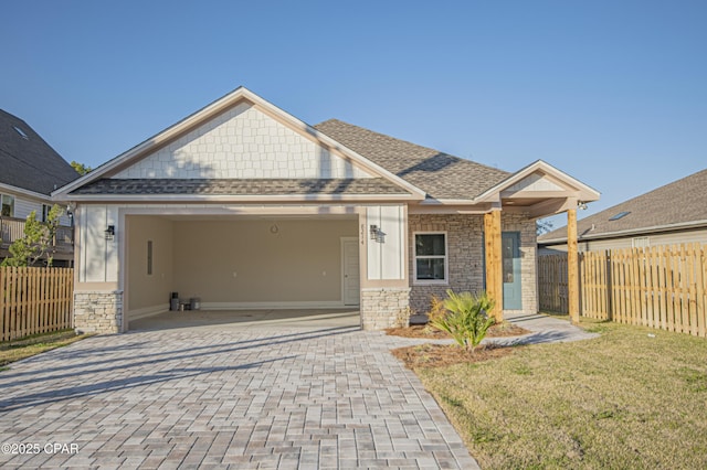 view of front facade with stone siding, decorative driveway, a garage, and fence