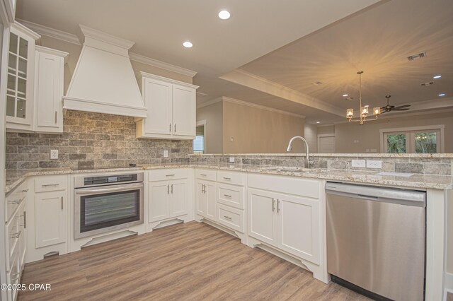 kitchen with custom exhaust hood, stainless steel oven, dark wood-type flooring, white cabinets, and sink