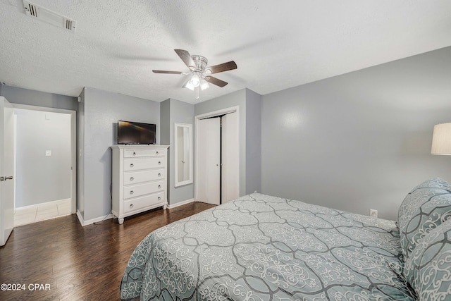 bedroom with a textured ceiling, dark wood-type flooring, ceiling fan, and a closet