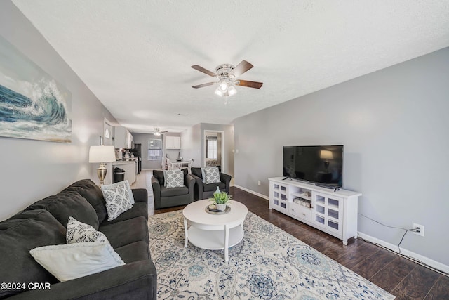 living room with ceiling fan, dark hardwood / wood-style floors, and a textured ceiling