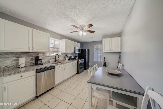 kitchen with stainless steel appliances, white cabinetry, sink, ceiling fan, and a textured ceiling