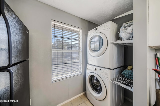 washroom featuring light tile patterned floors, a textured ceiling, and stacked washer / drying machine