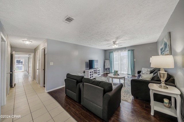 living room with a textured ceiling, a healthy amount of sunlight, hardwood / wood-style floors, and ceiling fan