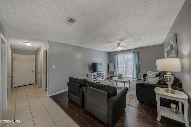 living room featuring ceiling fan, light hardwood / wood-style floors, and a textured ceiling