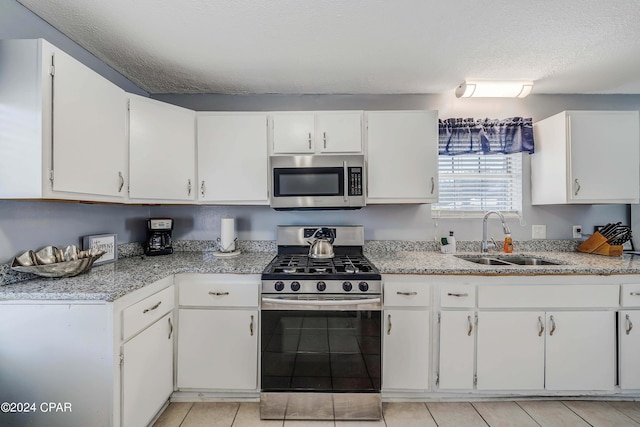 kitchen with white cabinetry, stainless steel appliances, sink, and a textured ceiling