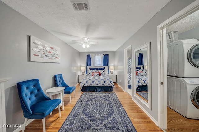 interior space with stacked washing maching and dryer, ceiling fan, wood-type flooring, and a textured ceiling