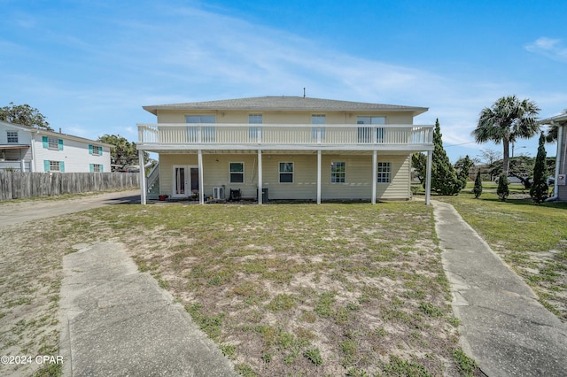 back of property featuring a balcony, a yard, and covered porch