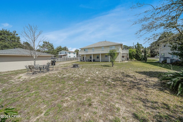 rear view of property with a yard, central AC unit, and an outdoor fire pit