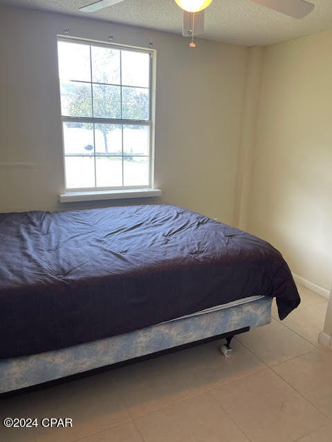 tiled bedroom featuring a textured ceiling and ceiling fan