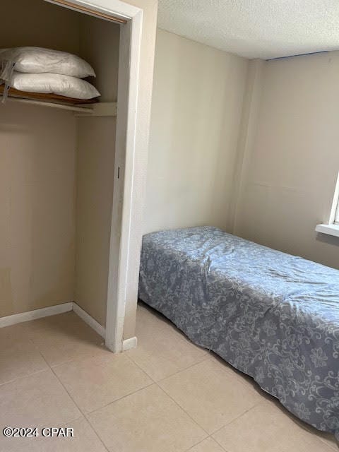 bedroom with a textured ceiling and tile patterned floors