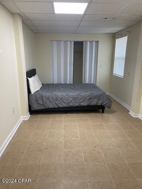 unfurnished bedroom featuring light tile patterned floors and a drop ceiling