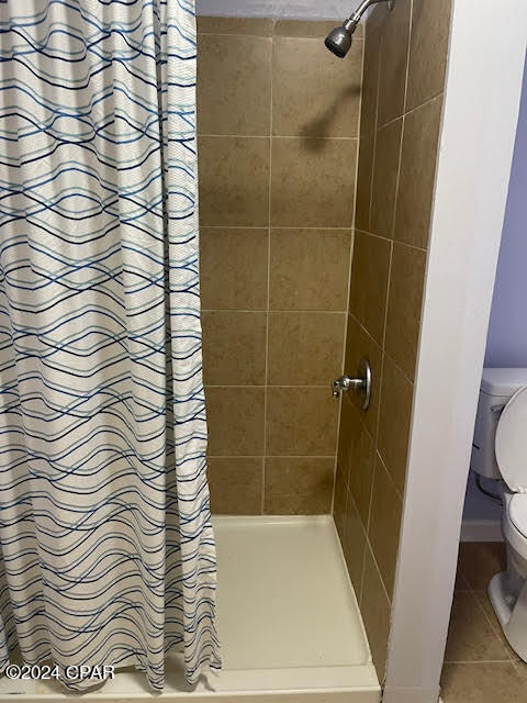 bathroom with tile patterned flooring, a shower with curtain, and toilet