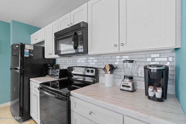 kitchen featuring light stone counters, light tile flooring, black appliances, tasteful backsplash, and white cabinetry