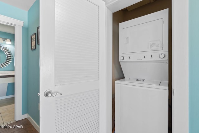 clothes washing area featuring stacked washer / drying machine and dark tile floors