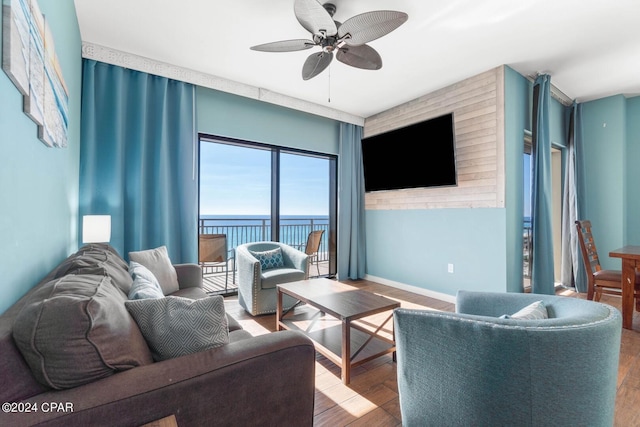 living room with light hardwood / wood-style flooring, ceiling fan, and a water view