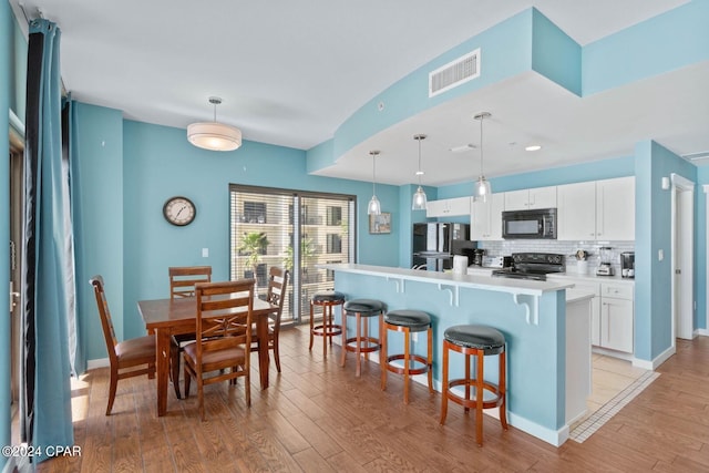 kitchen with white cabinetry, light hardwood / wood-style flooring, range with electric cooktop, tasteful backsplash, and pendant lighting