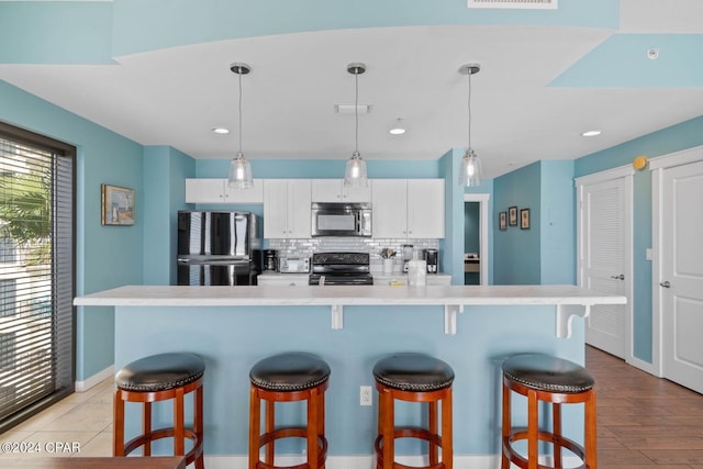 kitchen featuring a kitchen breakfast bar, appliances with stainless steel finishes, white cabinetry, backsplash, and hanging light fixtures