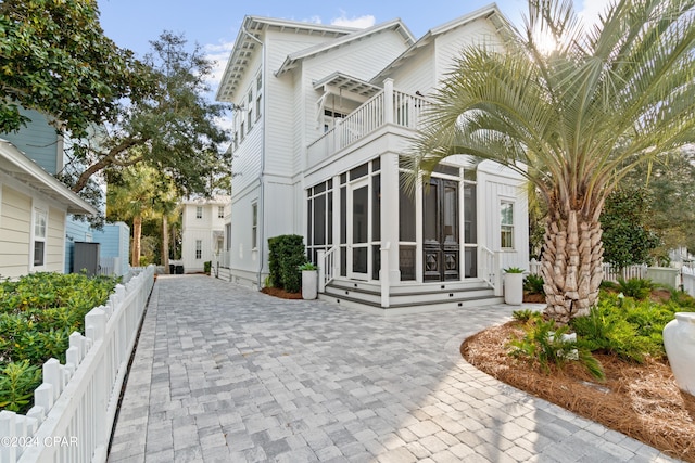 rear view of property featuring a balcony and a sunroom