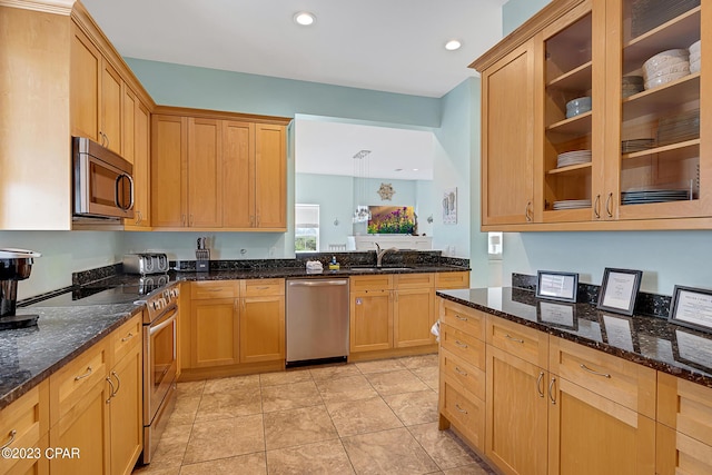 kitchen with light tile patterned flooring, appliances with stainless steel finishes, sink, and dark stone countertops