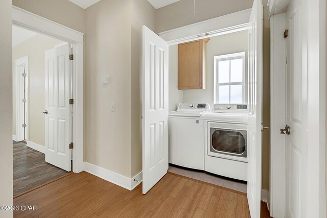 washroom featuring separate washer and dryer, light hardwood / wood-style flooring, and cabinets