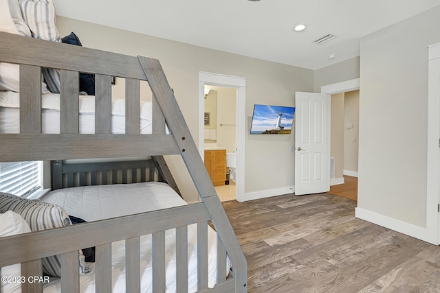 bedroom with hardwood / wood-style flooring and ensuite bathroom