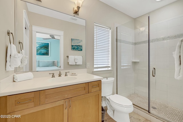 bathroom featuring vanity, a shower with shower door, and toilet