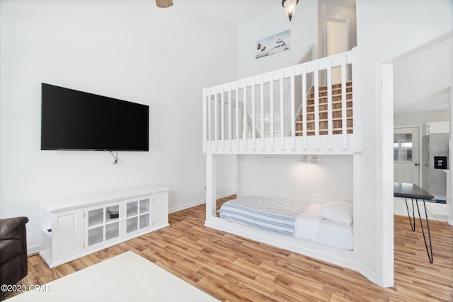 bedroom featuring stainless steel refrigerator with ice dispenser and light hardwood / wood-style floors