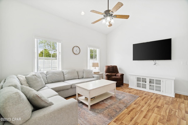 living room featuring light hardwood / wood-style flooring, high vaulted ceiling, and ceiling fan