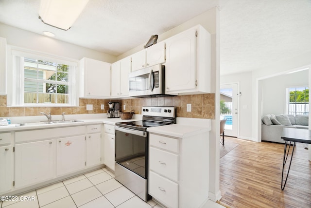 kitchen with sink, decorative backsplash, white cabinets, and appliances with stainless steel finishes