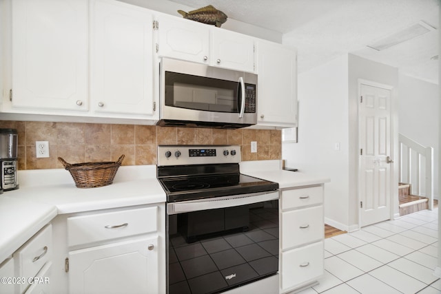 kitchen with tasteful backsplash, appliances with stainless steel finishes, light tile patterned floors, and white cabinets