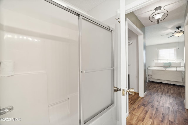 bathroom with hardwood / wood-style floors, a shower with shower door, a textured ceiling, and ceiling fan