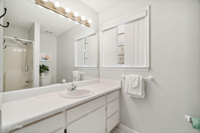 bathroom featuring vanity, toilet, and a shower