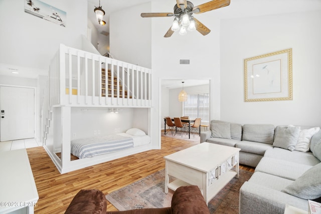 living room featuring dark hardwood / wood-style floors, ceiling fan, and a towering ceiling