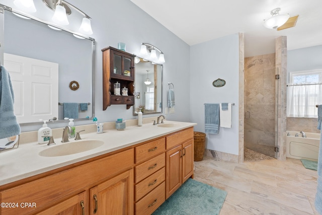 bathroom with tile floors, vanity with extensive cabinet space, separate shower and tub, and double sink