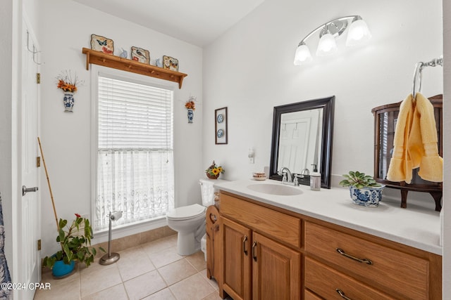 bathroom featuring toilet, a healthy amount of sunlight, vanity with extensive cabinet space, and tile flooring