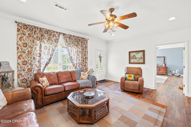 living room featuring ornamental molding, ceiling fan, and light wood-type flooring