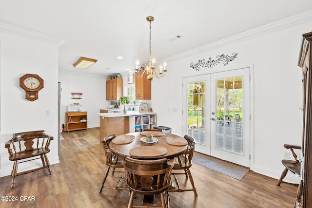 dining space featuring an inviting chandelier, crown molding, french doors, and hardwood / wood-style flooring