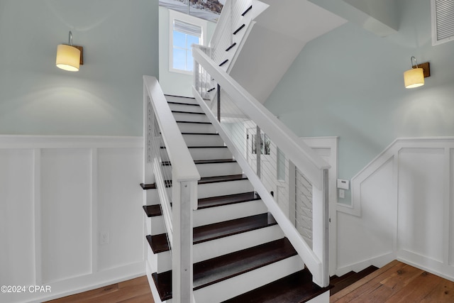 stairway with dark hardwood / wood-style floors and vaulted ceiling