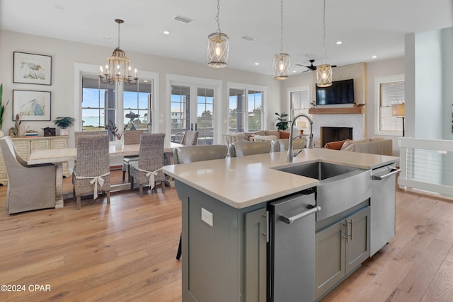 kitchen featuring light hardwood / wood-style floors, a fireplace, hanging light fixtures, and stainless steel dishwasher