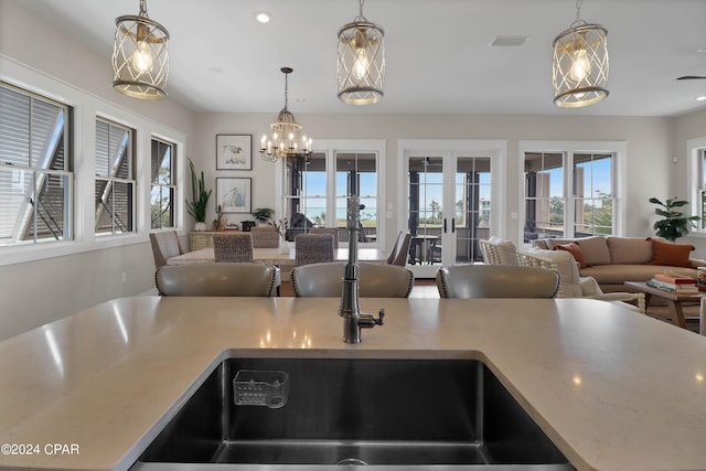 kitchen with french doors, an inviting chandelier, a kitchen island with sink, and a kitchen breakfast bar