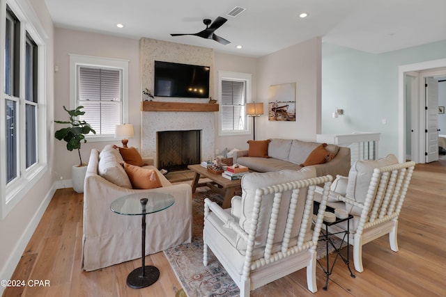 living room with a large fireplace, ceiling fan, and light hardwood / wood-style flooring