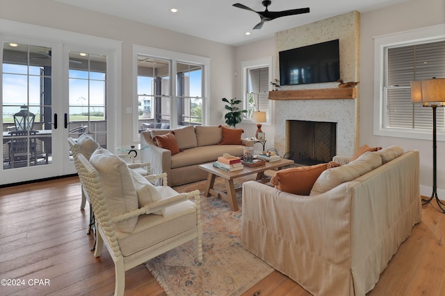 living room featuring a large fireplace, light hardwood / wood-style floors, and ceiling fan