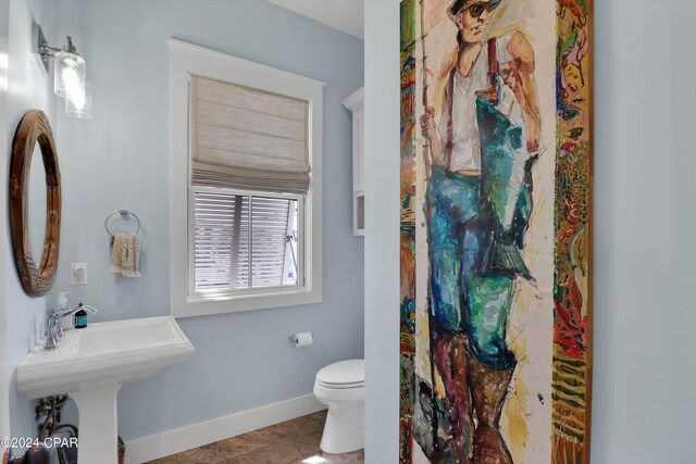 bathroom featuring toilet, tile flooring, and sink