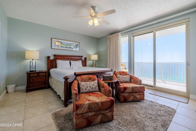 tiled bedroom featuring ceiling fan, a textured ceiling, access to exterior, and a water view