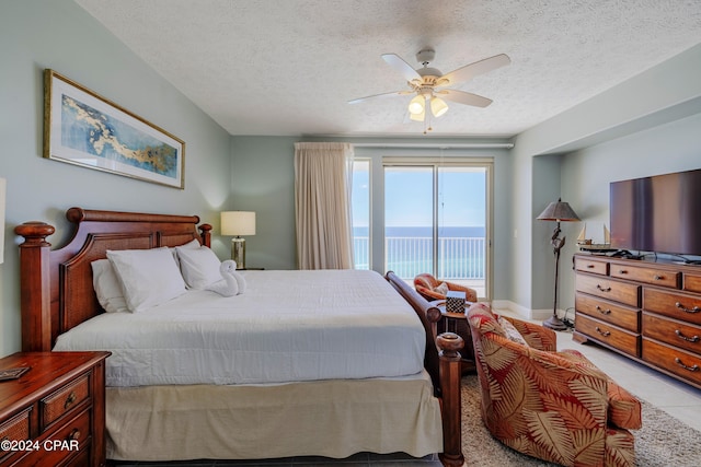 bedroom featuring ceiling fan, access to outside, light tile flooring, a water view, and a textured ceiling