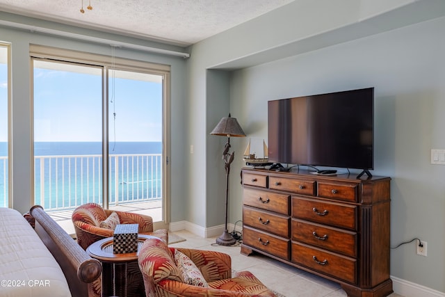 interior space featuring plenty of natural light, a textured ceiling, light tile flooring, and a water view