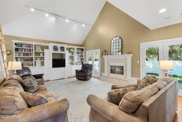 living room featuring french doors, a fireplace, light wood-style floors, track lighting, and high vaulted ceiling