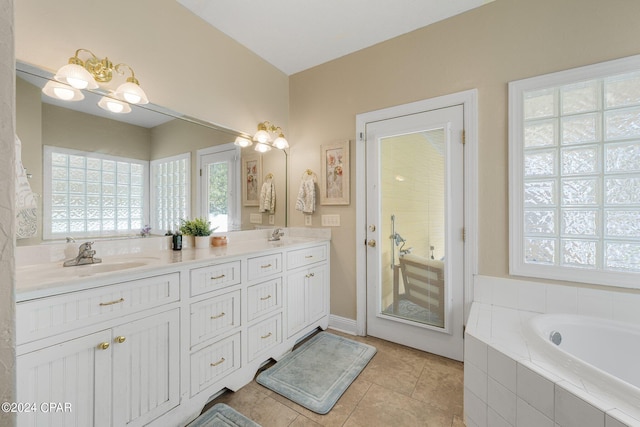 full bath with a sink, double vanity, a relaxing tiled tub, and tile patterned flooring