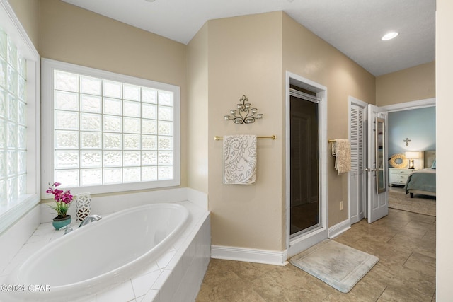 ensuite bathroom featuring baseboards, ensuite bath, a garden tub, tile patterned flooring, and a shower stall