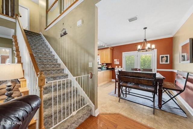 interior space with a notable chandelier, visible vents, ornamental molding, wood finished floors, and baseboards